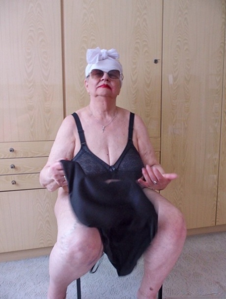 Naughty chubby granny Melba plays with her saggy tits while undressing
